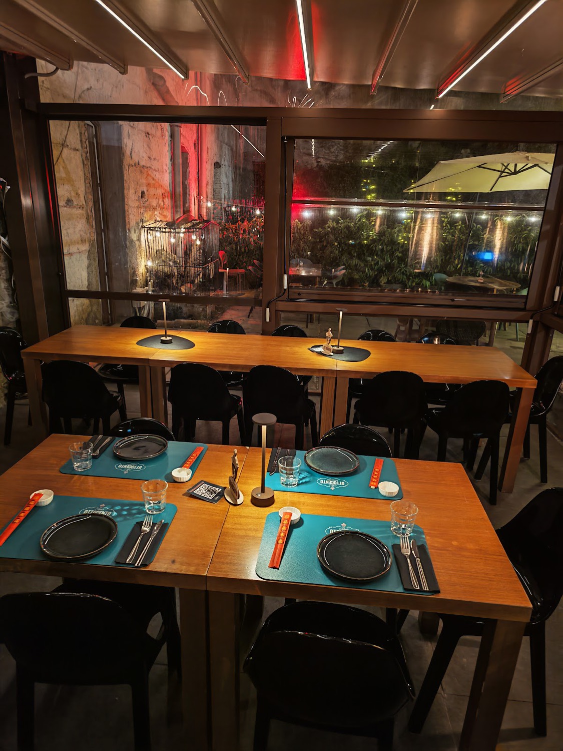 La sala di Osteria Ottocento la sera, con la pietra a vista e le luci calde